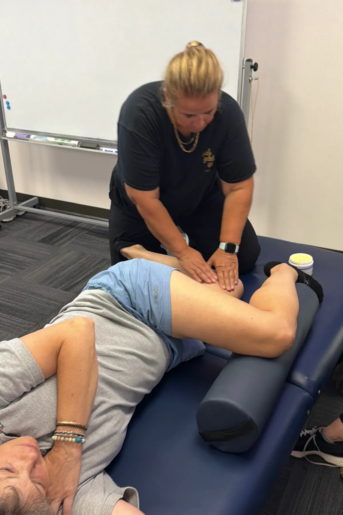 Yodi Richeson working hands-on on a client's hamstring as they lie on their side on a treatment table