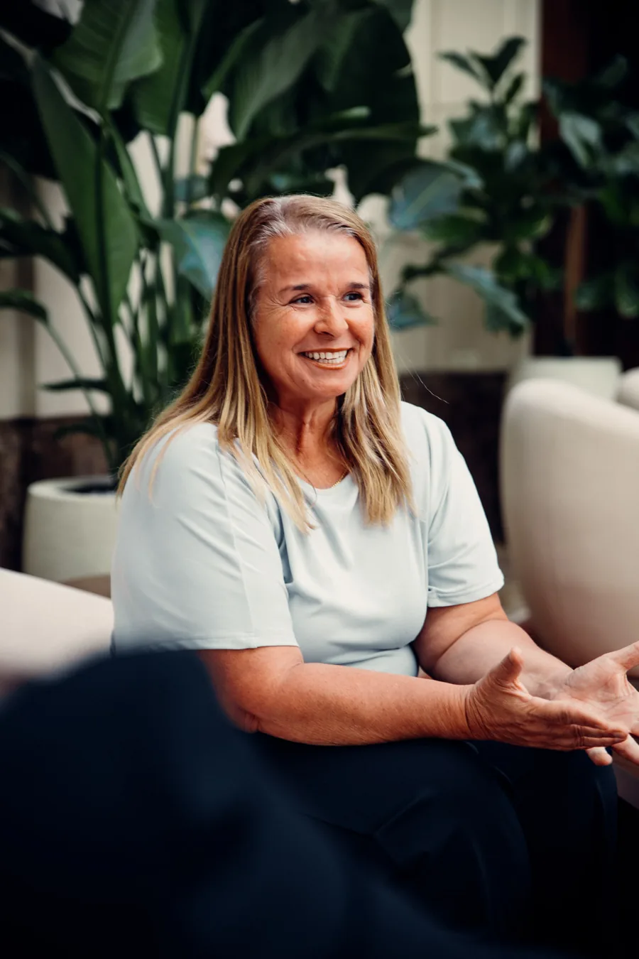 Yodi Richeson smiling and gesturing mid-conversation, seated in a lounge
