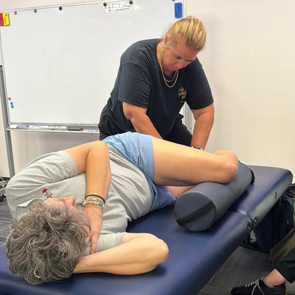 Yodi Richeson working hands-on on the back of a client's leg as they lie on their side on a treatment table