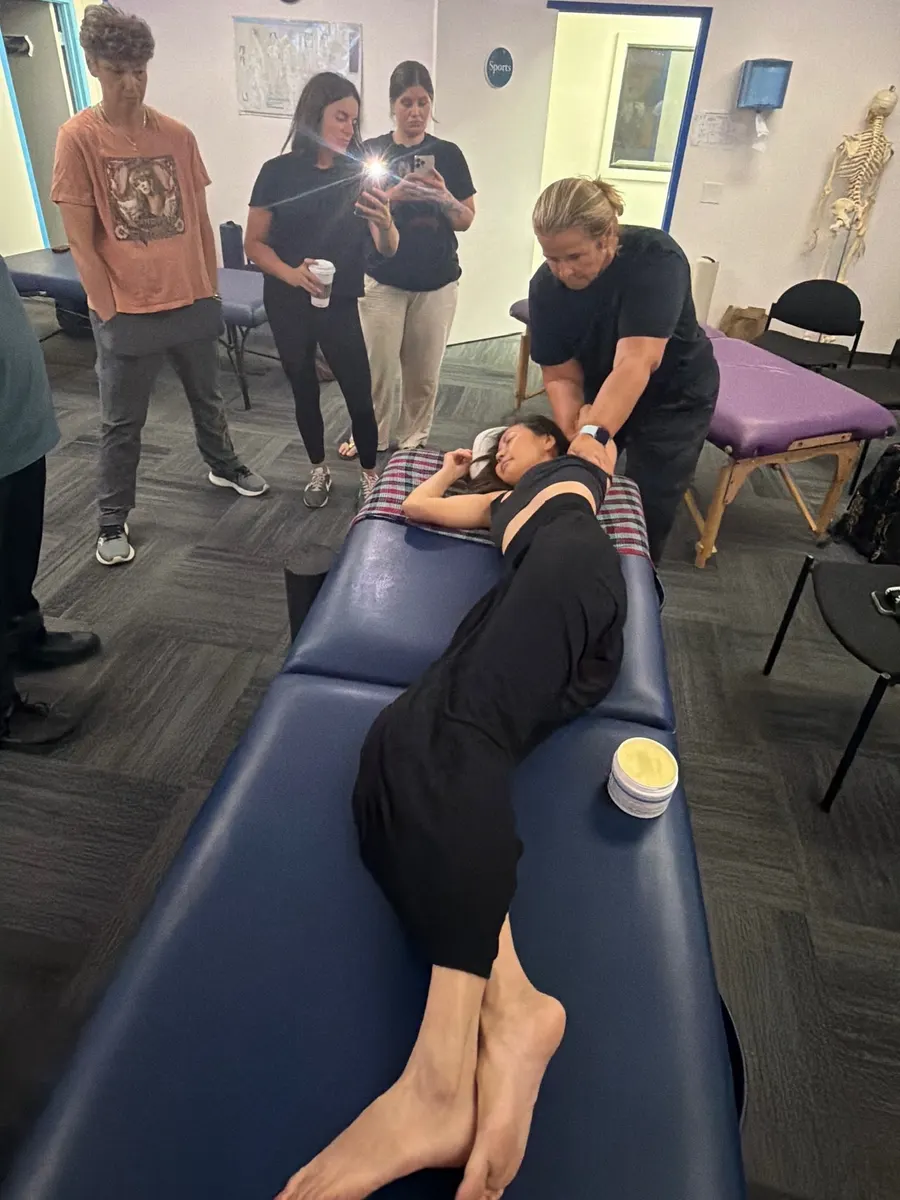 Yodi Richeson demonstrating a technique on a client while a class of practitioners watches